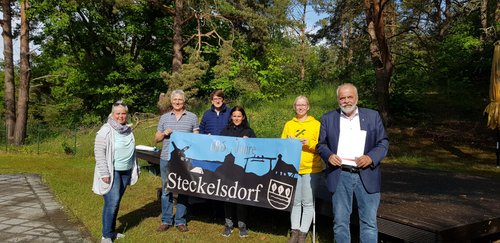Bürgermeister, Ortsvorsteher und Mitglieder des Heimatvereins mit einem Banner des Ortsteils Steckelsdorf
